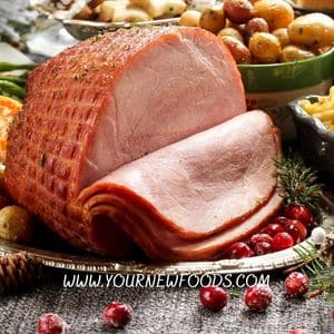 cooked ham joint on a table with cooked veg and potatoes