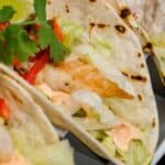 three mexican fish tacos on a white oval plate