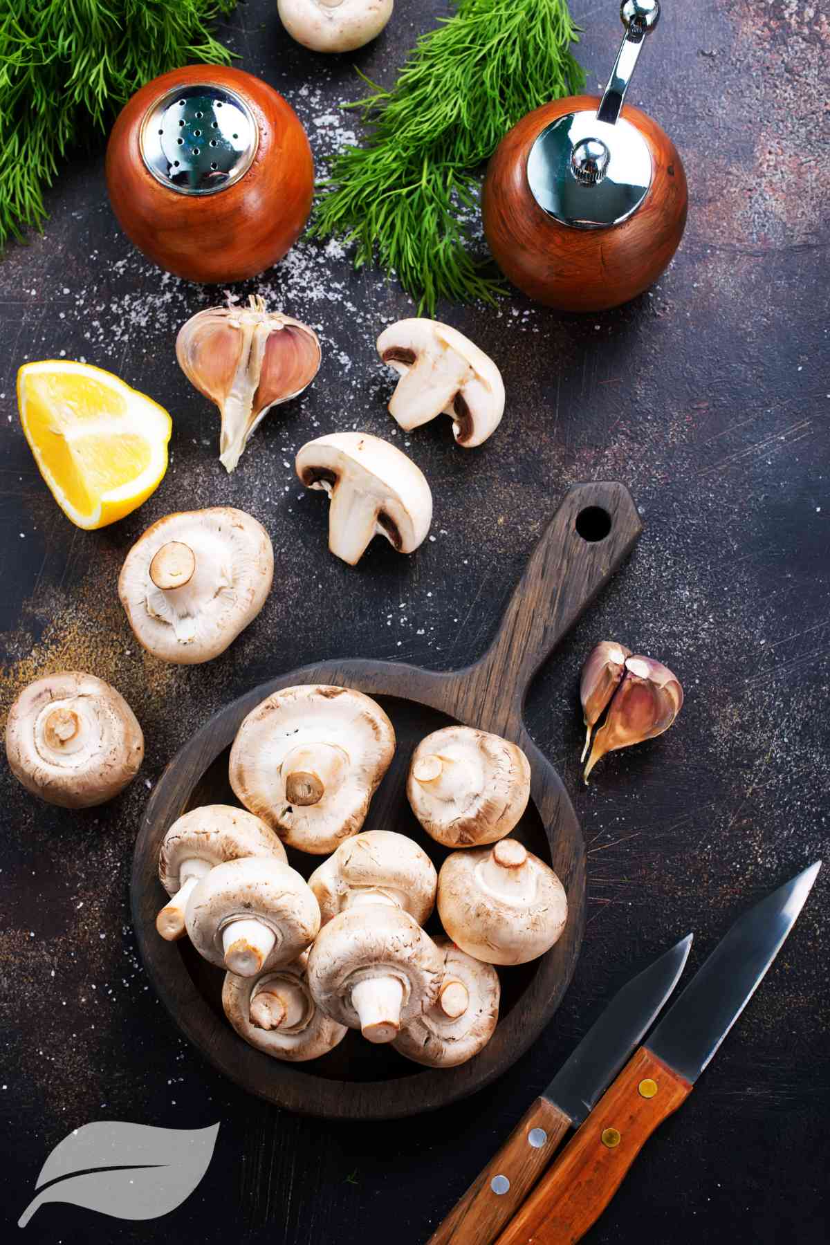Raw mushrooms on a wooden bowl with a quarter lemon and garlic