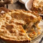 Chicken pie with diced vegetables and a piece of pie cut out