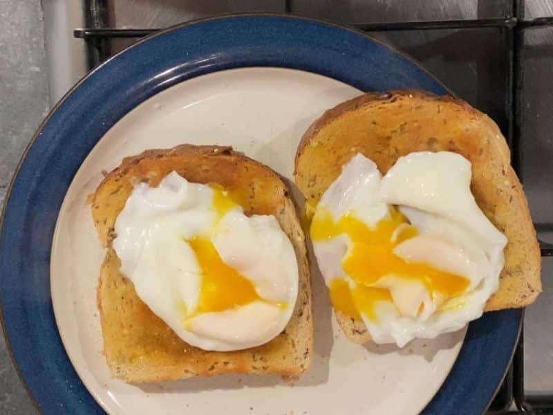 two poached eggs on wholemeal toast with the yolk popped
