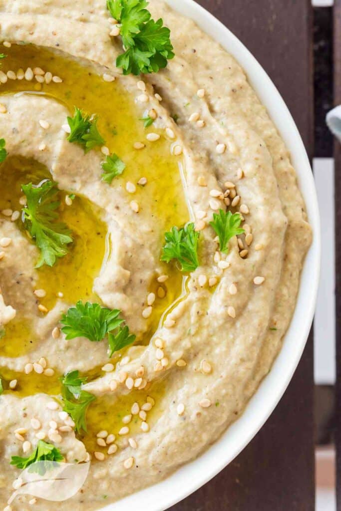 Hummus in a white bowl with olive oil on top