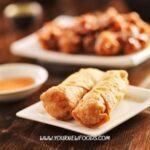 Chinese food recipes egg rolls on a white plate whhich is a on dark brown wooden table. These can be made with the chinese food recipes on these pages