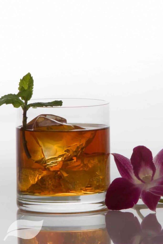 rum cocktail in a tumbler next to a purple flower