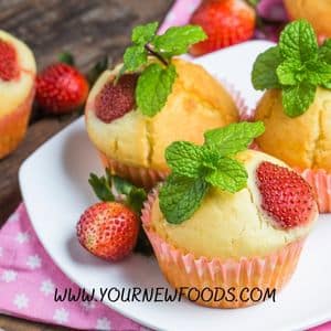 strawberry muffins on a plate with whole strawberries