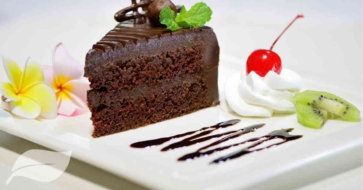 chocolate dessert on a white plate will a swirl of cream and a cherry on top